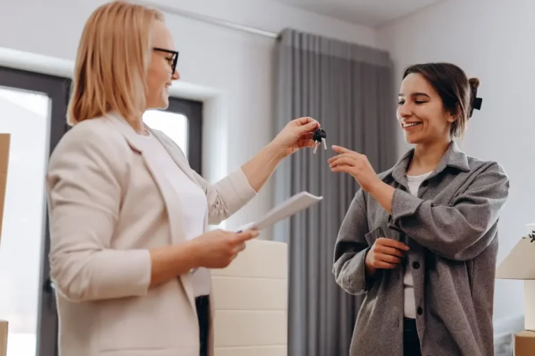 A woman handing over keys to another person